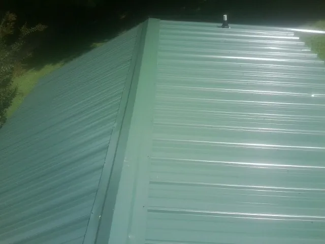 New green metal panels meeting at the ridge of a roof — Flat Roof Repair work by our crew in Graysville