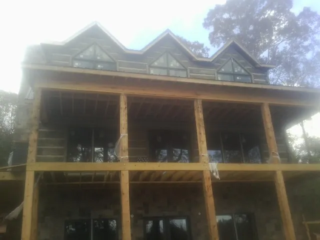 Dormers and porch framing on a large log home under construction — Roof Coating work by our crew in Graysville