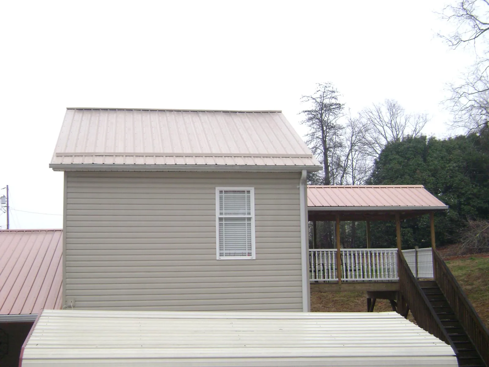 Tan metal roofs on a two story addition and attached porch, from a Roof Replacement job in Graysville